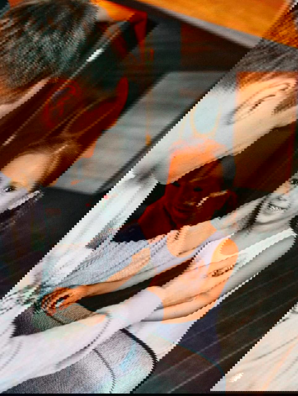 Мужчина нежно общается с маленькой улыбающейся девочкой в домашней обстановке — теплый семейный кадр с улыбками.