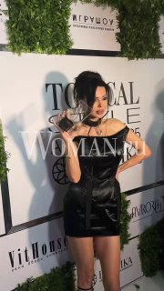 Кадр: Оксана Самойлова в чёрном мини-платье с наградой «Икона стиля» на фоне баннера Topical Style Awards.