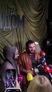 JONY выступает у микрофонов на презентации альбома «Рядом»: артист говорит в пресс-центр, рядом люди в капюшонах и множество микрофонов