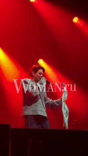 Артист на сцене держит предмет в руках, насыщенное красно‑оранжевое освещение и дымовая атмосфера, кадр крупным планом