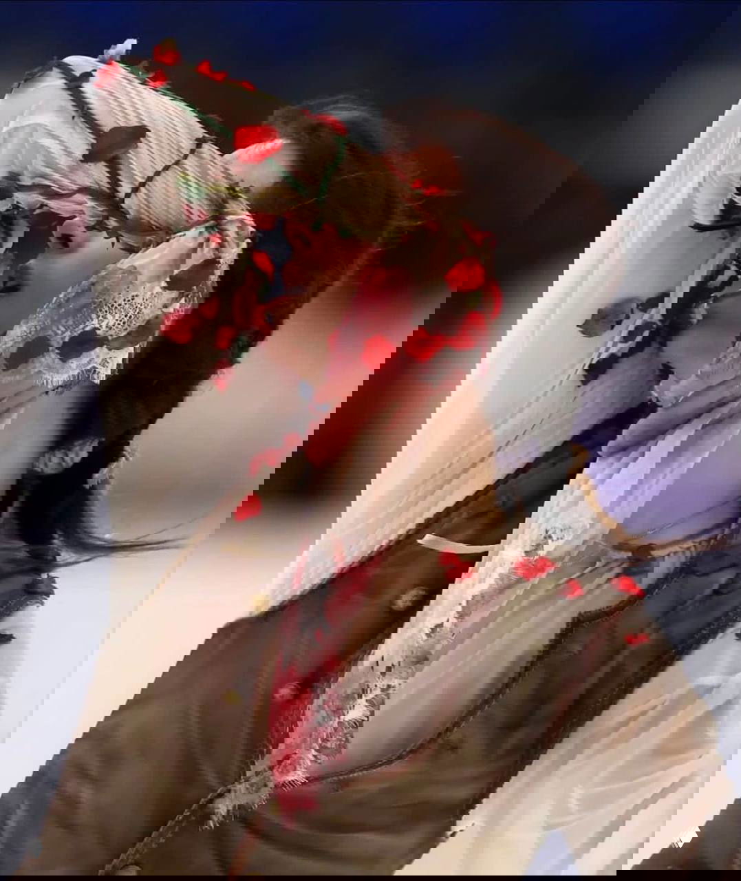 Крупный план полупрозрачной блузы Петра Гуменника: кружево и расшитые красные лепестки на рукаве во время выступления.