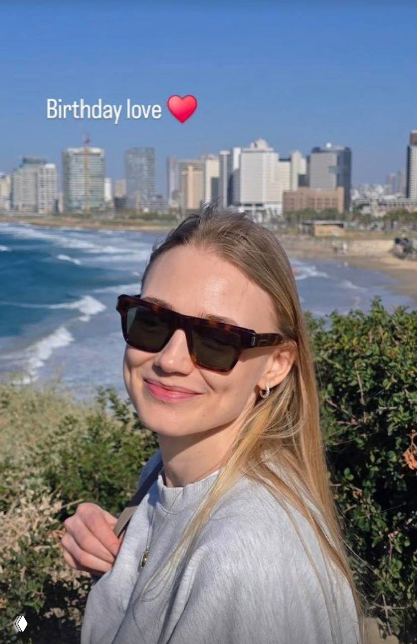 Оксана Акиньшина улыбается в солнечных очках на фоне побережья и города; на фото видна подпись «Birthday love» и сердечко.