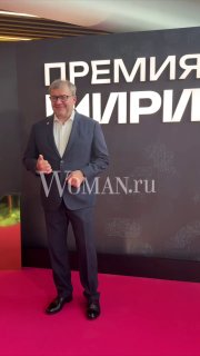 Михаил Пореченков в тёмном костюме стоит на красной дорожке у баннера «ПРЕМИЯ ИРИ», улыбается и позирует для фотографий.