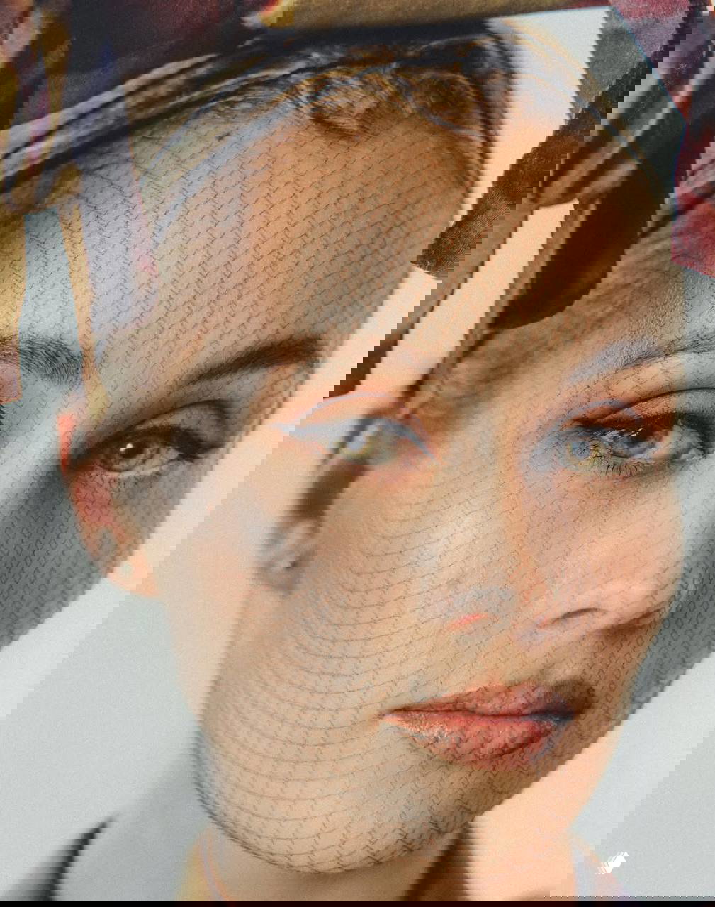 Крупный план лица Маш Милаш в сетчатой вуали: натуральный макияж, зелёные глаза и рисунок сетки на коже, подчёркнутый студийным светом.