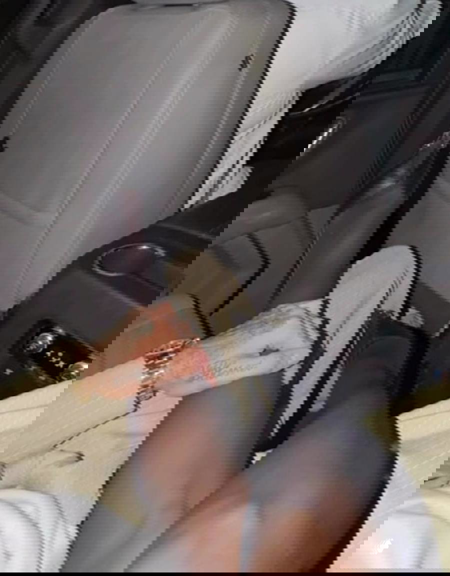 Ночная фотография в салоне автомобиля: женские ноги в чулках и татуированная мужская рука на колене, интимный фрагмент поездки пары.