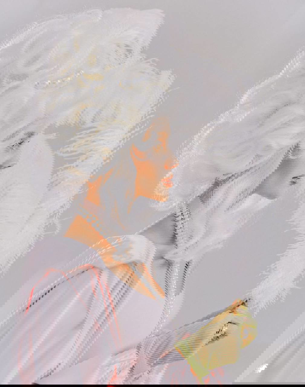 Профильный портрет Маш Милаш в белом парике в стиле рококо с перьями и жемчугом, в перчатках и с реквизитом в руках, мягкое студийное освещение.