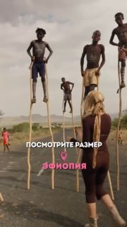 Люди на высоких ходулях в сельском пейзаже; сцена как из поездки в Эфиопию — местные в традиционной одежде на фоне неба.