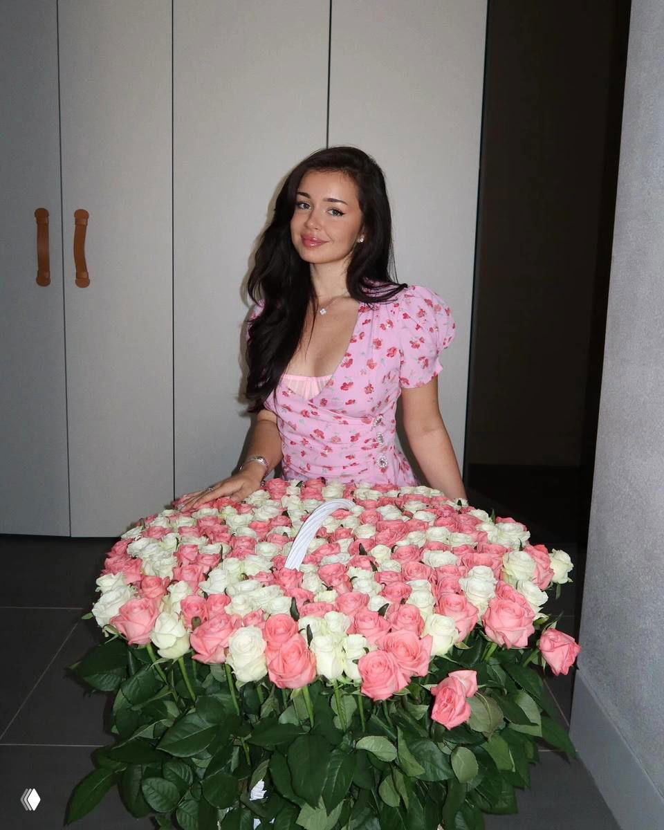 Ника сидит за большой корзиной роз розово-белых оттенков в платье, фотография сделана в интерьере — крупный план букета и автора поста.