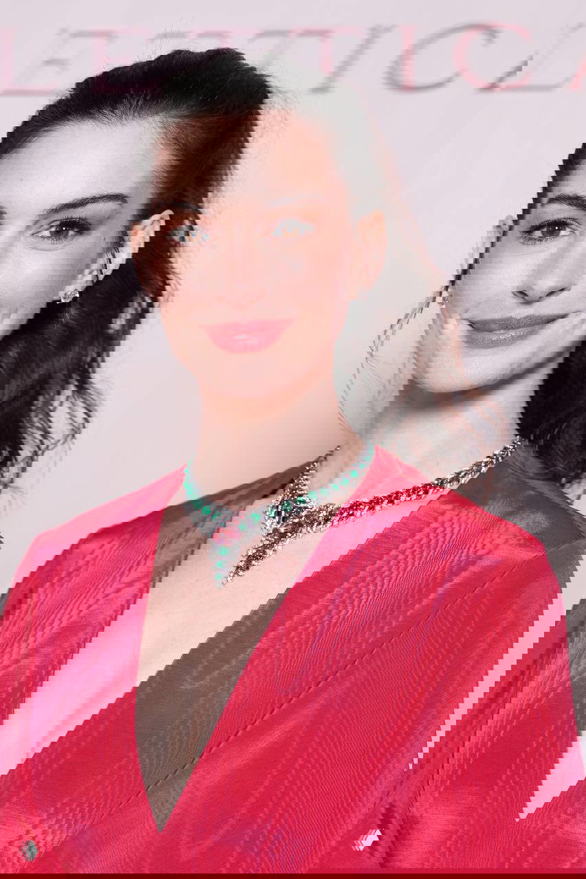 Крупный план Энн Хэтэуэй в розовом платье: ожерелье Bvlgari с зелёными камнями, лёгкий макияж и причёска конский хвост.