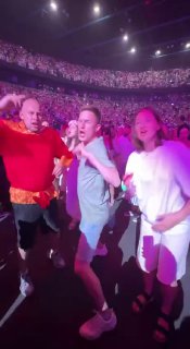 Зал концерта с толпой зрителей и несколькими людьми у сцены при ярких прожекторах — иллюстрация популярности артистов и корпоративных шоу.