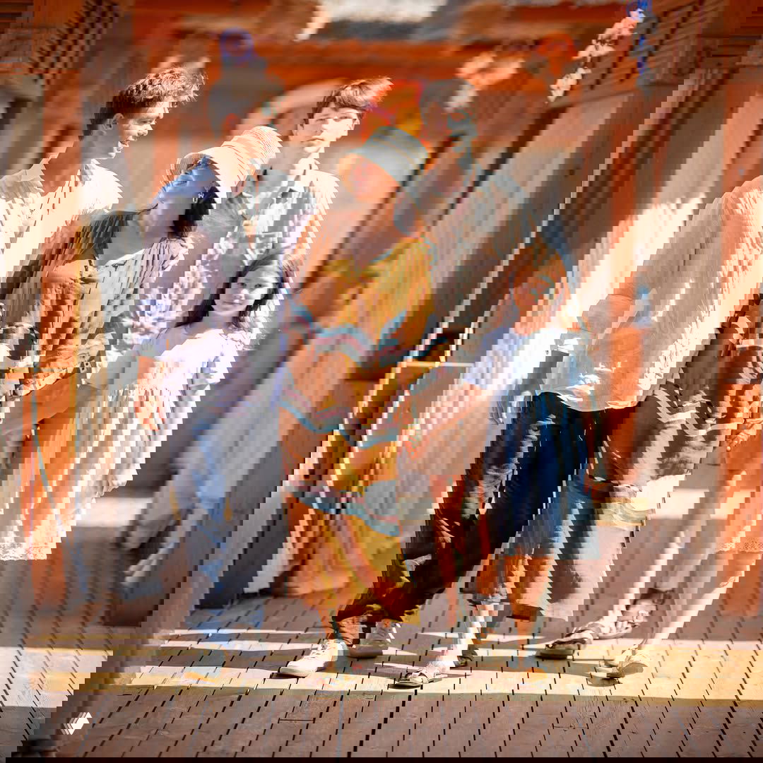 Екатерина Климова идёт рука об руку с детьми по деревянной набережной у моря: семейная прогулка в пляжном комплексе в тёплый день.