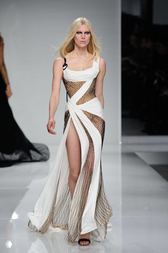 Модель на подиуме в платье Versace из весна‑лето 2016: сетчатые вставки, высокий разрез и драпировка, снимок с показа.