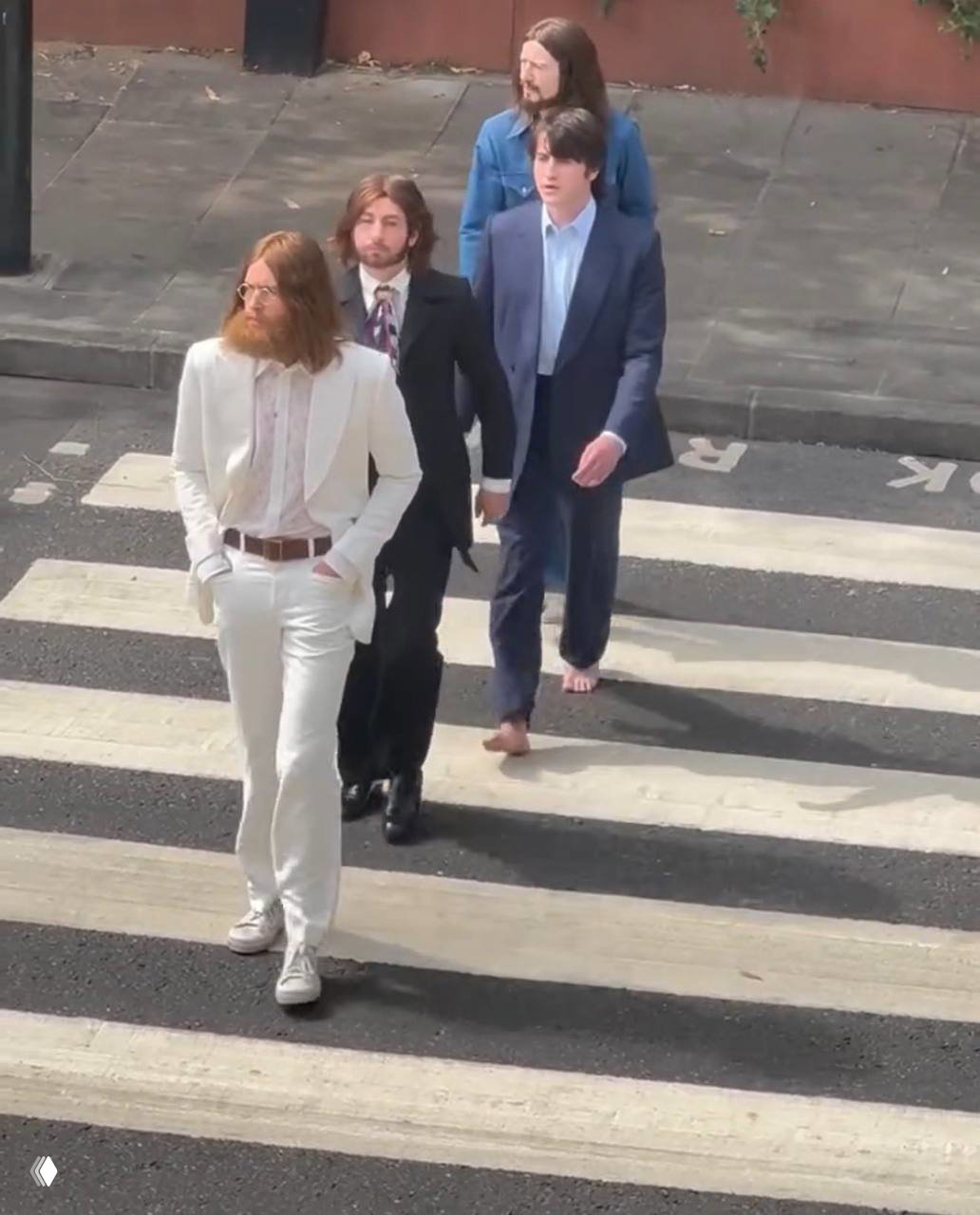 Реконструкция кадра Abbey Road: актеры, исполняющие музыкантов в фильме Сэма Мендеса, идут по пешеходному переходу; один из них идет босиком.