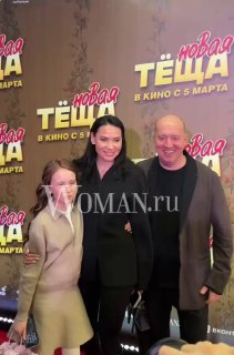 Сергей Бурунов с избранницей Екатериной Леви и девочкой на красной дорожке премьеры фильма «Новая тёща», на фоне баннера с постером и названием фильма