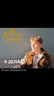 Вертикальное фото молодого человека в коричневой куртке на светлом фоне; портретный кадр с логотипом или графикой в верхней части изображения.