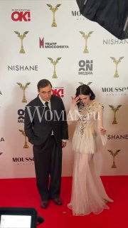 Пара в вечерних нарядах стоит у брендволла на церемонии «Ника», фото подчёркивает их образы и атмосферу премии