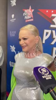 Лариса Долина в серебристом платье даёт интервью на фоне баннера фестиваля «Звезды Русского Радио в Завидово», рядом виден микрофон