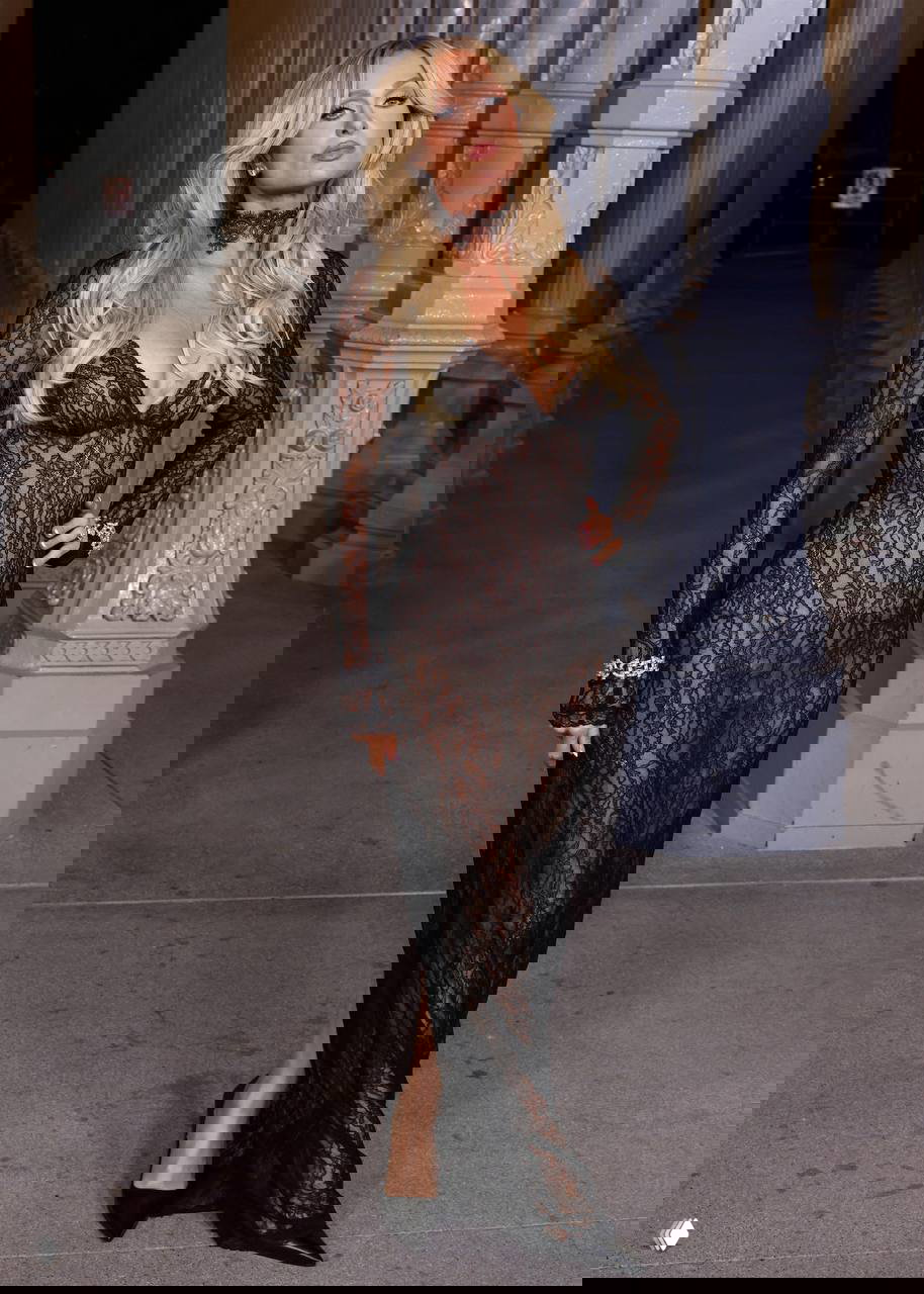 Женщина в длинном чёрном кружевном платье позирует на открытом городском фоне у архитектурных колонн, вечерняя прогулка в элегантном стиле.