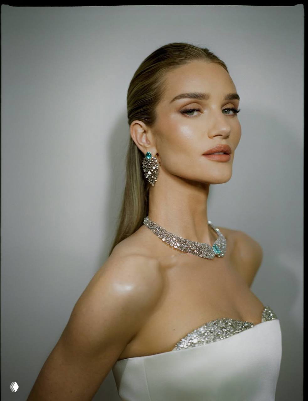 Крупный план Рози Хантингтон-Уайтли в серьгах и ожерелье Tiffany с бирюзовыми акцентами; нюдовый макияж и гладкая причёска.