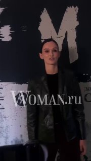 Паулина Андреева в тёмном пиджаке и чёрной рубашке на фоне баннера с логотипом Woman.ru — портретный кадр с мероприятия