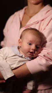 Вертикальный кадр с мамой Сашей Трусовой и ребёнком Мишей — тёплое домашнее видео с близким планом, смягчённое освещение.