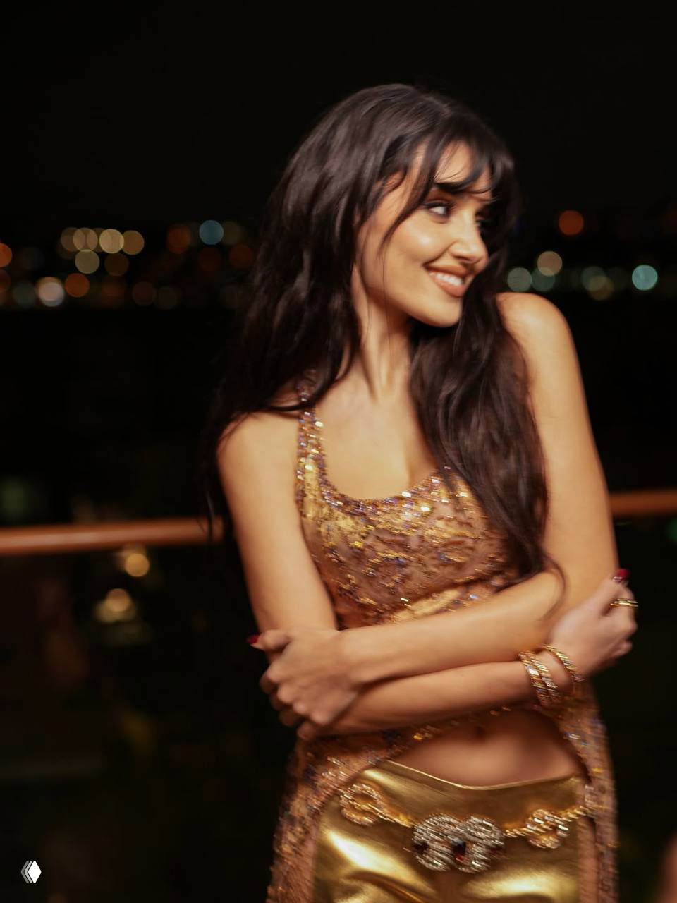 Улыбающаяся женщина в высококонтрастном тёплом освещении на фоне ночного города, полуоборот и декоративные блики на заднем плане