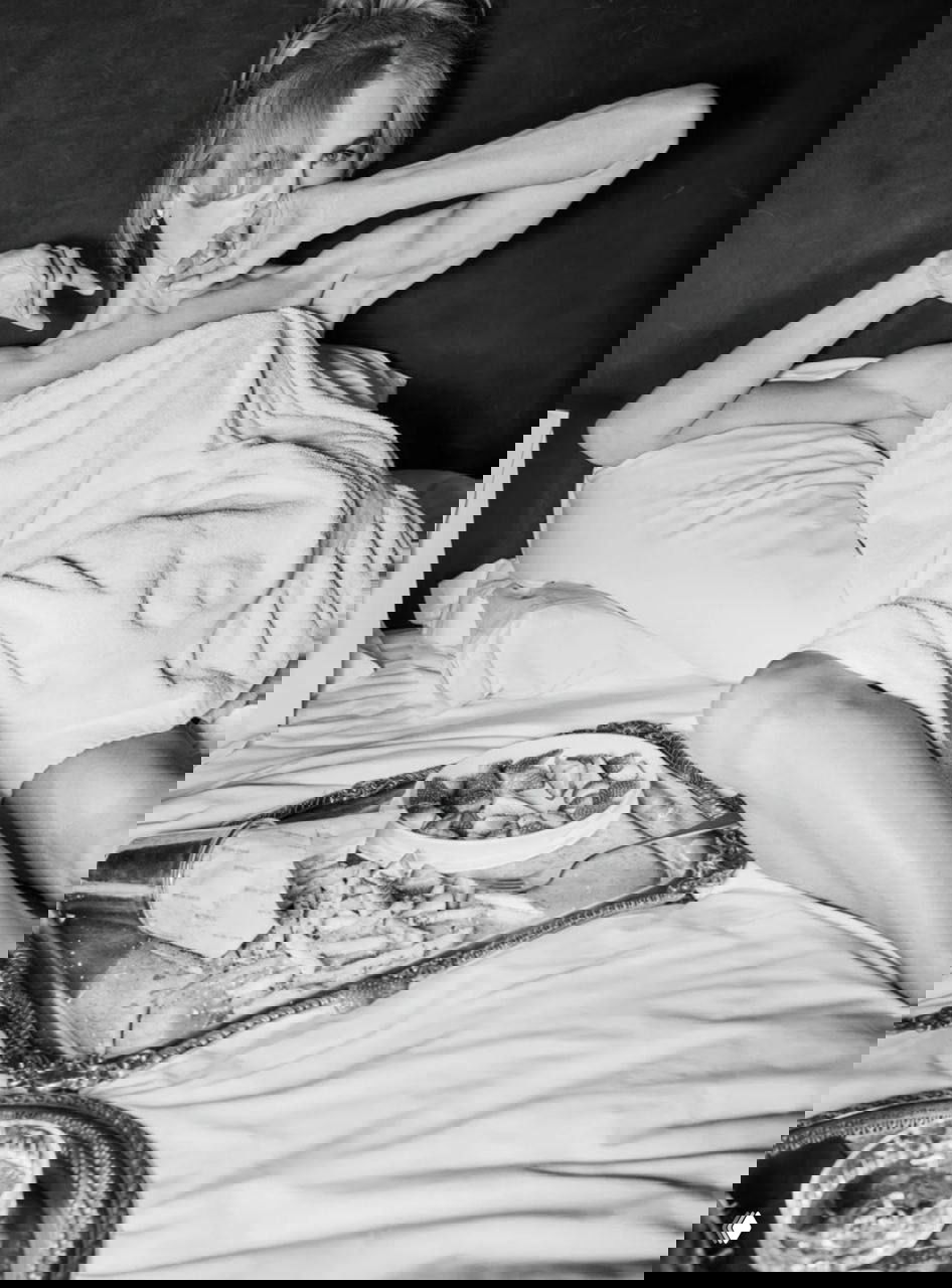 Чёрно‑белый кадр: Николь Кидман в постели, укрыта простынёй, рядом поднос с закусками — интимный и кинематографичный студийный снимок.