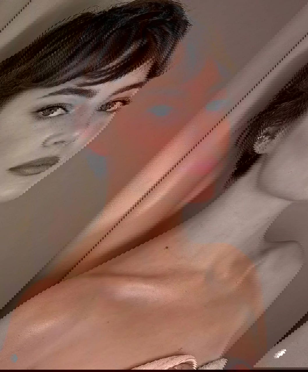 Крупный портретный кадр с естественным макияжем и короткой стрижкой в нейтральной гамме — акцент на лице и плечах.