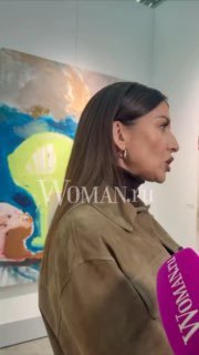 Певица Жасмин в профиль на фоне яркой картины на ярмарке «Арт Россия», говорит в микрофон во время открытия.