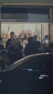Ночное прибытие звезды: большая толпа и охрана у входа, фанаты снимают на телефоны и подсветкой — кадр с концерта в Алматы.