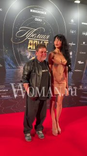 Александр Цекало и его жена Дарина Эрвин стоят на красной дорожке премии АПКиТ в вечерних образах — полный рост, фотоснимок на фоне баннера