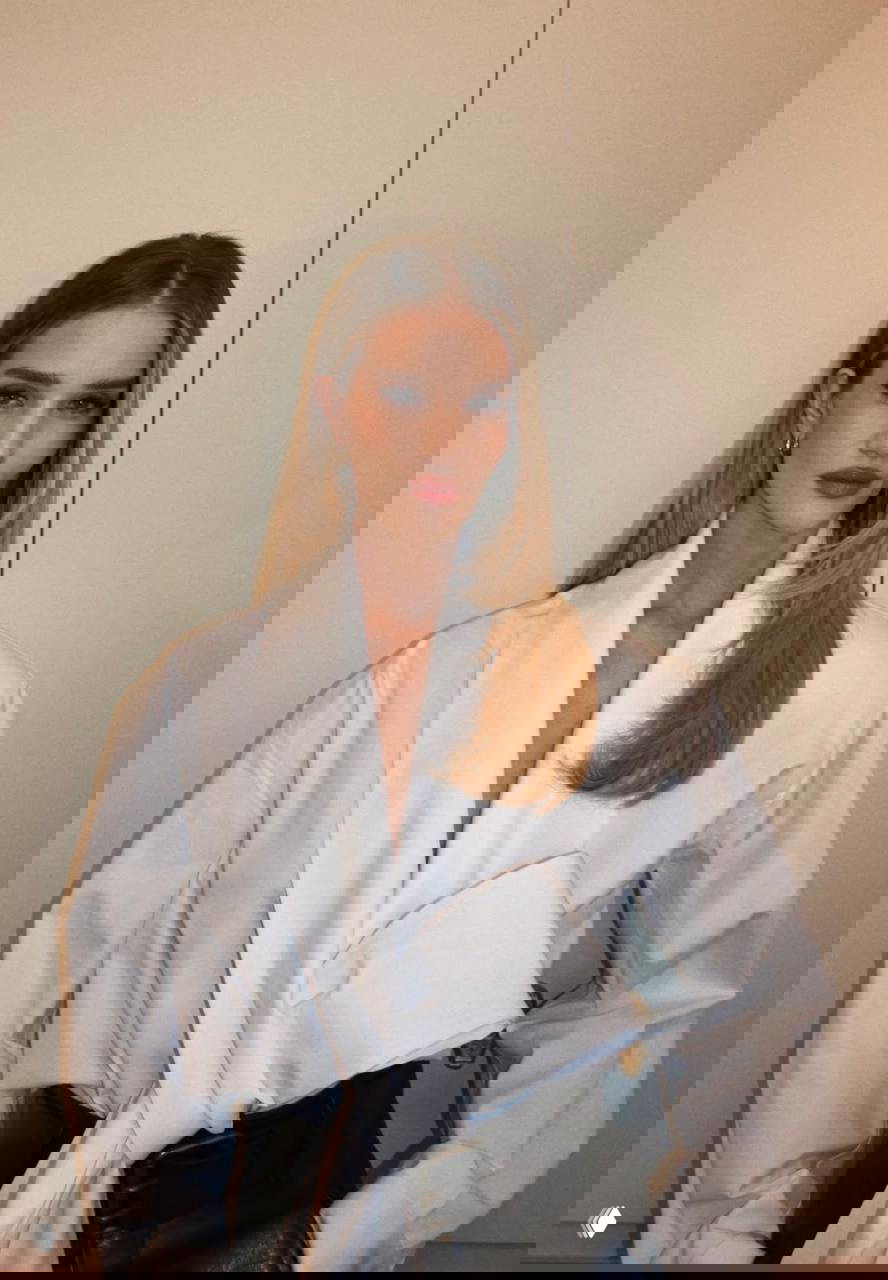 Портрет Роузи в светлой блузе и аккуратной причёске, крупный план лица с естественным макияжем и серьгами, нейтральный фон.