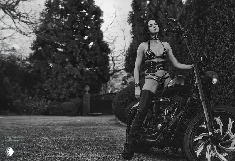 Чёрно-белый кадр с динамическими артефактами, где модель в боди и сапогах запечатлена в движении на открытой площадке — стилизованный fashion-шот.