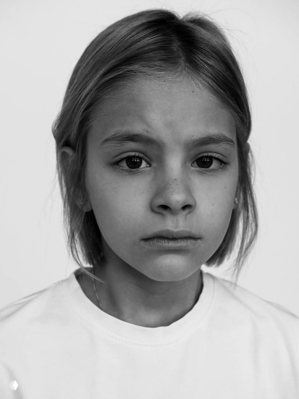 Полноразмерный портрет девочки в белой футболке и джинсах, студийный минимализм, спокойная поза и задумчивое выражение.