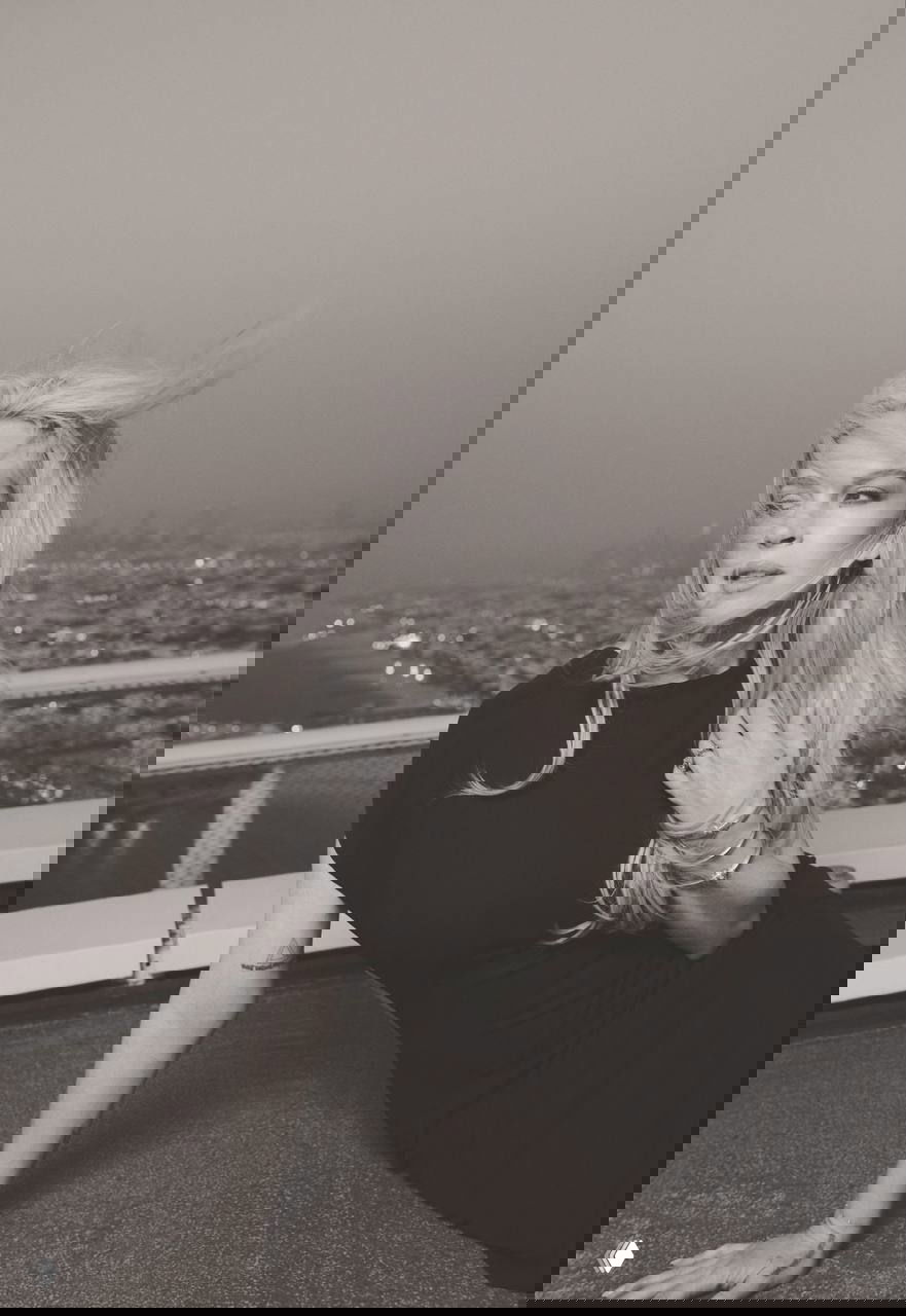 Чёрно‑белый портрет Линдси Лохан на крыше: волосы развеваются, взгляд в сторону, атмосферный и художественный кадр.