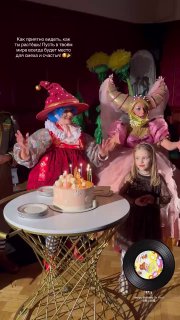 Мила на дне рождения: девочка сидит за столом с тортом и зажжёнными свечами, рядом два аниматора в сказочных костюмах и праздничные украшения.