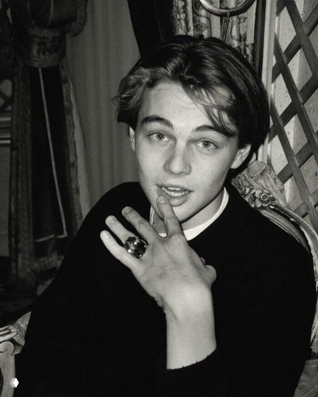 Чёрно‑белый ретро‑портрет молодого Леонардо ДиКаприо: выразительный взгляд, лёгкая игра эмоций и рука около лица в артистичной позе.