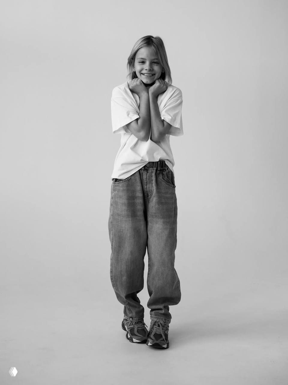 Черно‑белый портрет девочки, лицо крупным планом, шутливый кадр с высунутым языком — естественная детская мимика и задор.