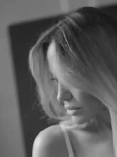 Чёрно‑белый крупный план женщины в профиль, мягкое освещение, задумчивая поза и полуоткрытое плечо в интимной картинке.