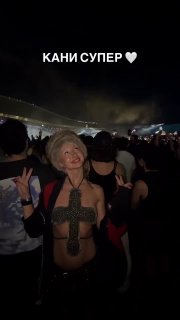 Чёрнота ночной сцены и веселящаяся женщина в откровенном наряде с крестом из украшений, публика на фоне и надпись "КАНИ СУПЕР".