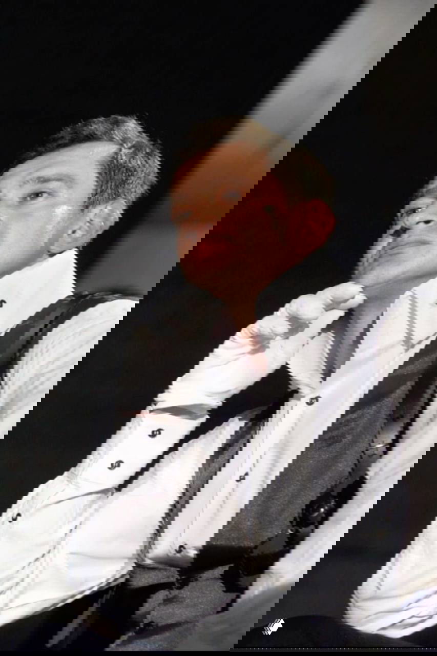 Мужчина в сценическом костюме и белых перчатках, выражение лица задумчивое, театральный ряд снимков в постановочном свете.