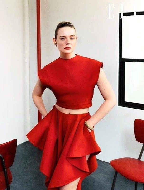 Эль Фаннинг в красном двучастном наряде, позирует в студии у окна — портретная фотография из фотосессии для Elle.