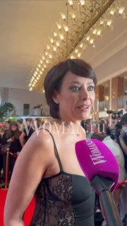 Крупный план Екатерины Волковой во время интервью на вручении «Ника», перед ней микрофон с логотипом Woman.ru и толпа гостей на фоне