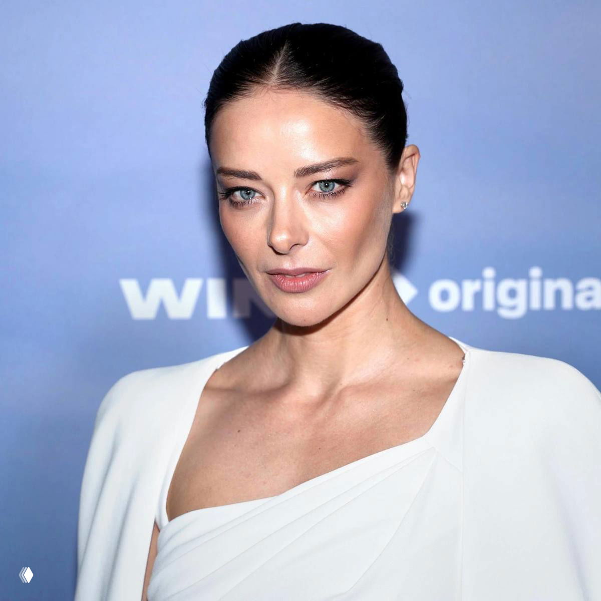 Крупный план актрисы в белом наряде: выразительные глаза и скулы, студийный свет и светло-голубой фон.