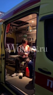 Интерьер скорой помощи: мужчина сидит внутри машины на носилках, видны медицинское оборудование и открытая дверь, сцена для репортажа Woman.ru