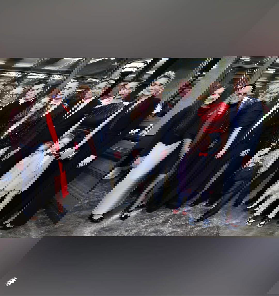 Большая групповая фотография гостей и членов семьи в фойе: несколько поколений, вечерние наряды и семейная атмосфера.