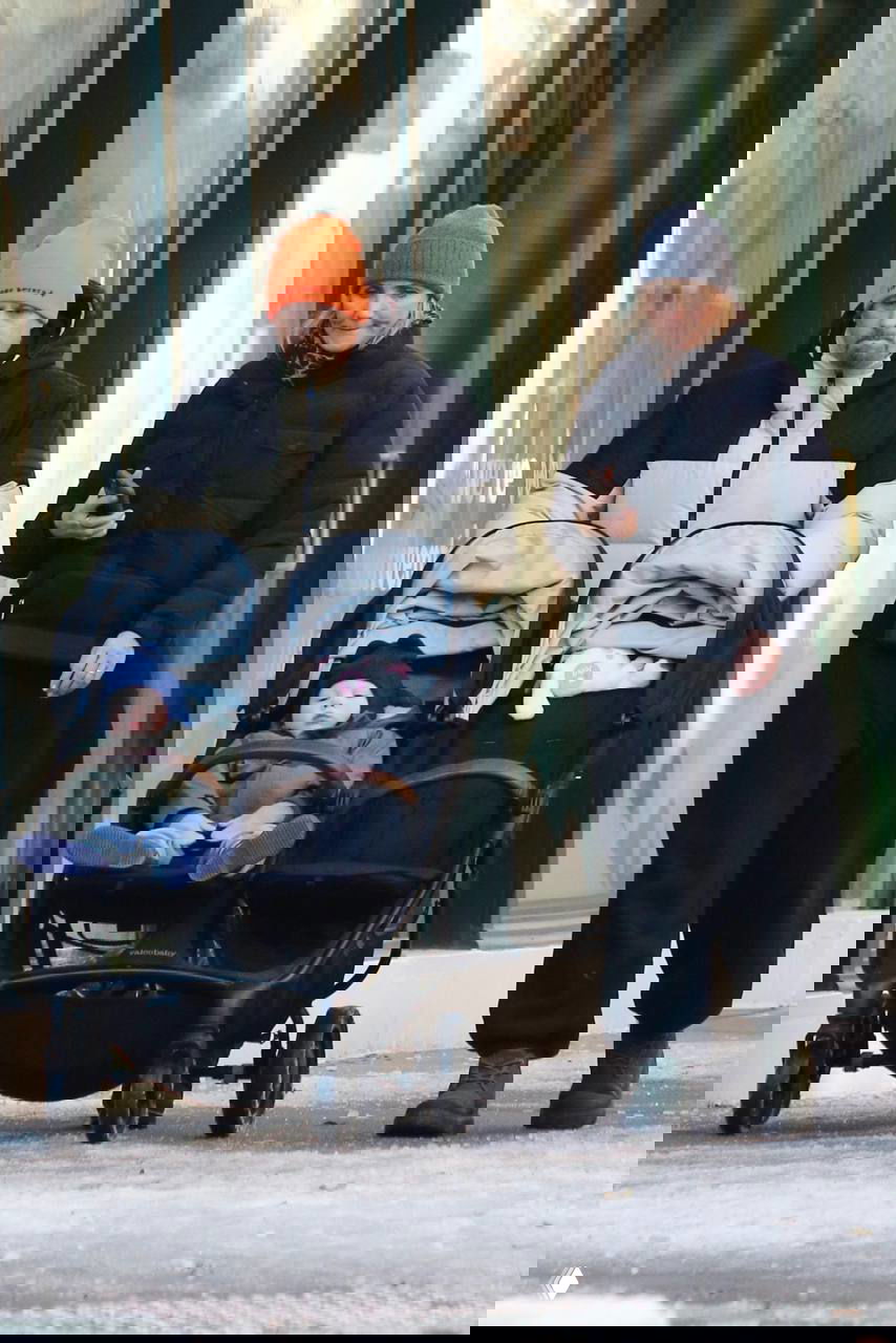 Кэмерон Диаз идёт по тротуару Нью-Йорка рядом с супругом и двойной коляской с ребёнком; уличный кадр папарацци, зимняя прогулка семьи.