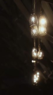 Размытое крупное фото вертикально висящих декоративных подвесных светильников в тёплом желтоватом свете, боке и отражения.