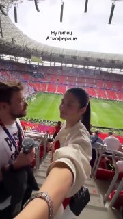 Вид с трибуны на пустеющую или заполненную часть стадиона, человек в переднем плане показывает атмосферу финала Лиги чемпионов и боления.