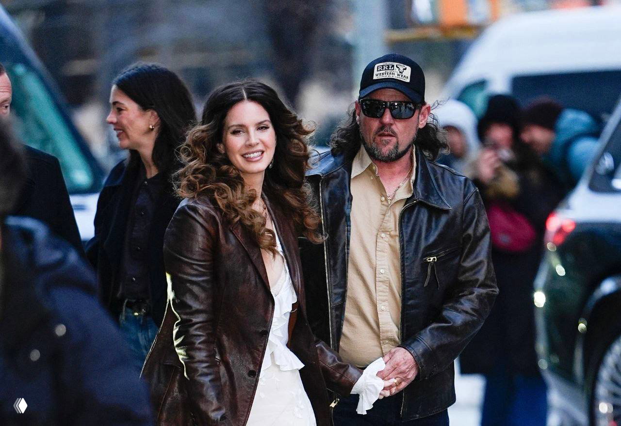 Лана Дель Рей и Джереми Дюфрен идут по улице, держась за руки после показа Ralph Lauren; в кадре прохожие и автомобили.